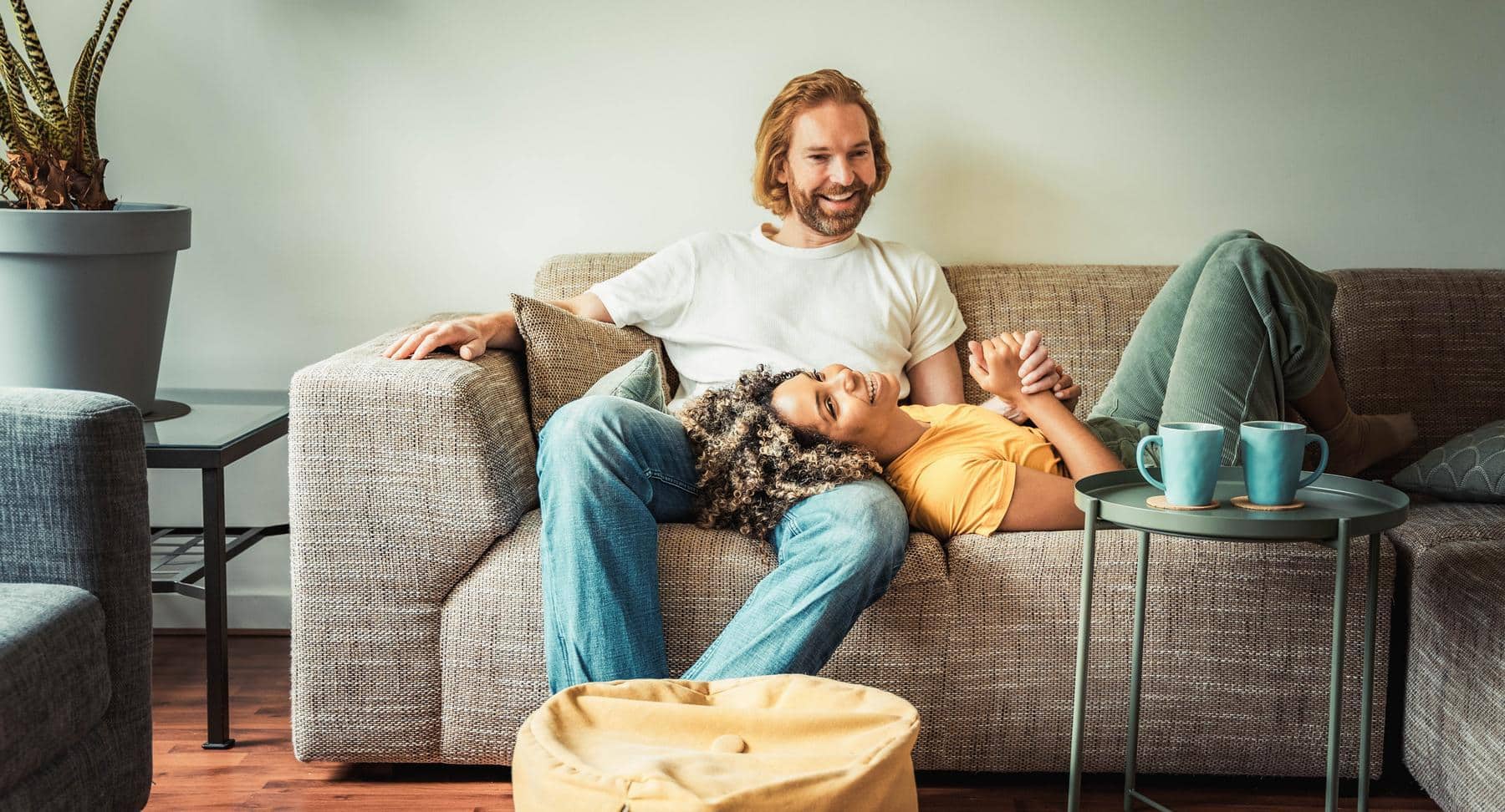 Happy couple relaxing and laughing on couch in apartment